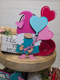 Colorful heart-shaped balloon cutout with a wooden box in the background